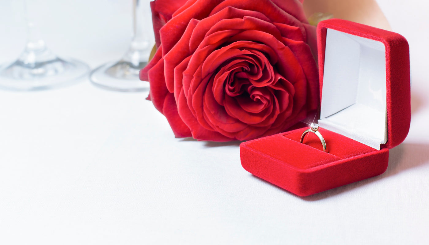 Diamond ring in a red box next to a red rose