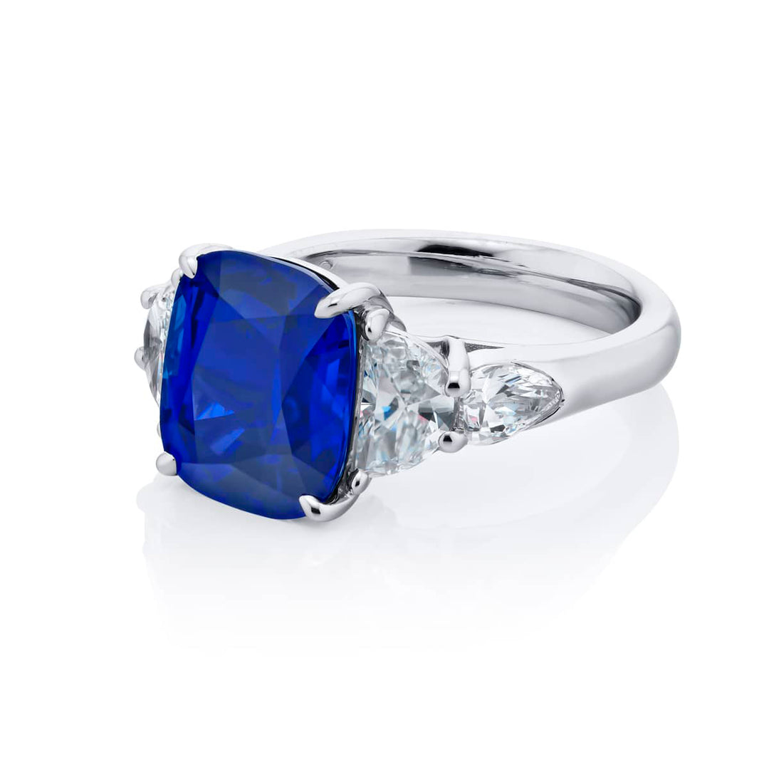Breathtaking Radiance: Our stunning 7.04 ct. certified Sri Lankan Sapphire Ring. This beautiful cushion-cut sapphire crowned in dazzling shield and half-moon diamonds is handcrafted in pure platinum.