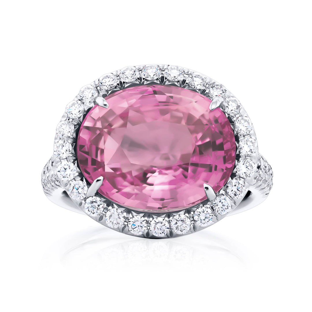 Breathtaking Radiance: Our magnificent 10.17 ct. certified Padparadscha Sapphire Ring. This stunning oval padparadscha sapphire embraced by tapered baguette and micro pave diamonds is handcrafted in pure platinum.