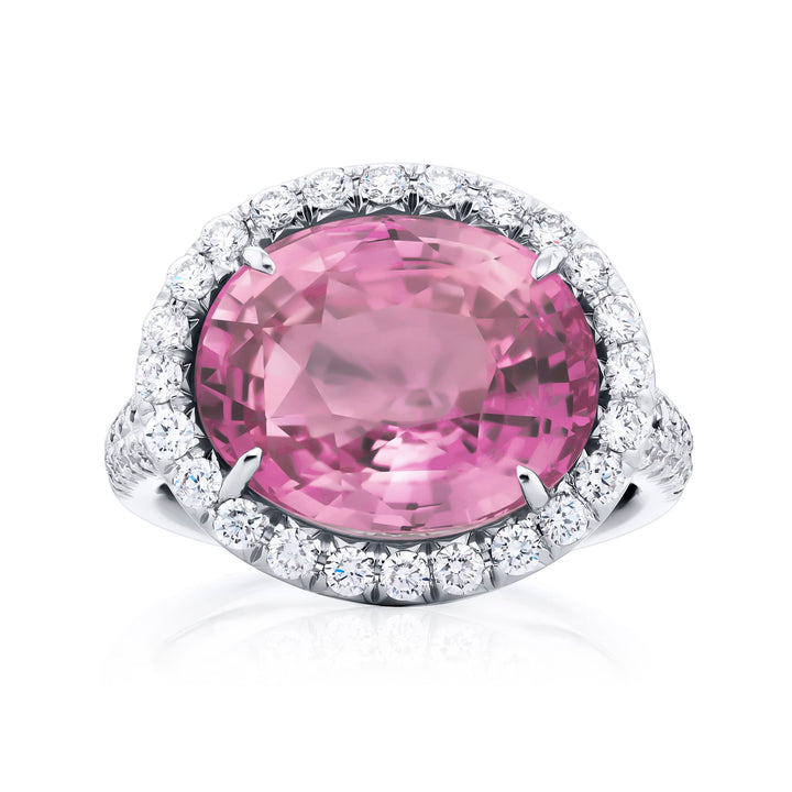 Breathtaking Radiance: Our magnificent 10.17 ct. certified Padparadscha Sapphire Ring. This stunning oval padparadscha sapphire embraced by tapered baguette and micro pave diamonds is handcrafted in pure platinum.