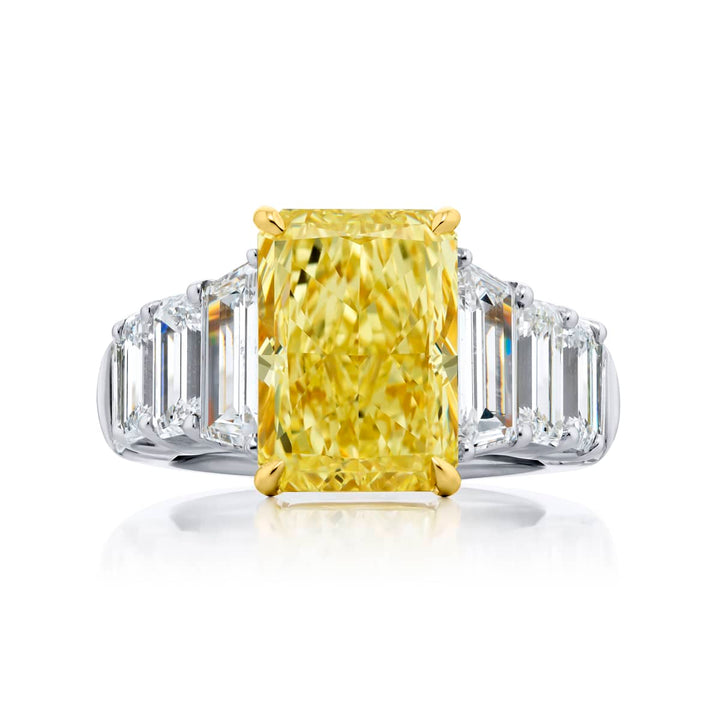 Dazzling Brilliance: Our magnificent 5.66 ct. GIA certified Fancy Yellow Diamond Ring. This beautiful radiant-cut fancy yellow diamond flanked by emerald-cut and trapezoid diamonds is handcrafted in pure platinum and 18KY gold.
