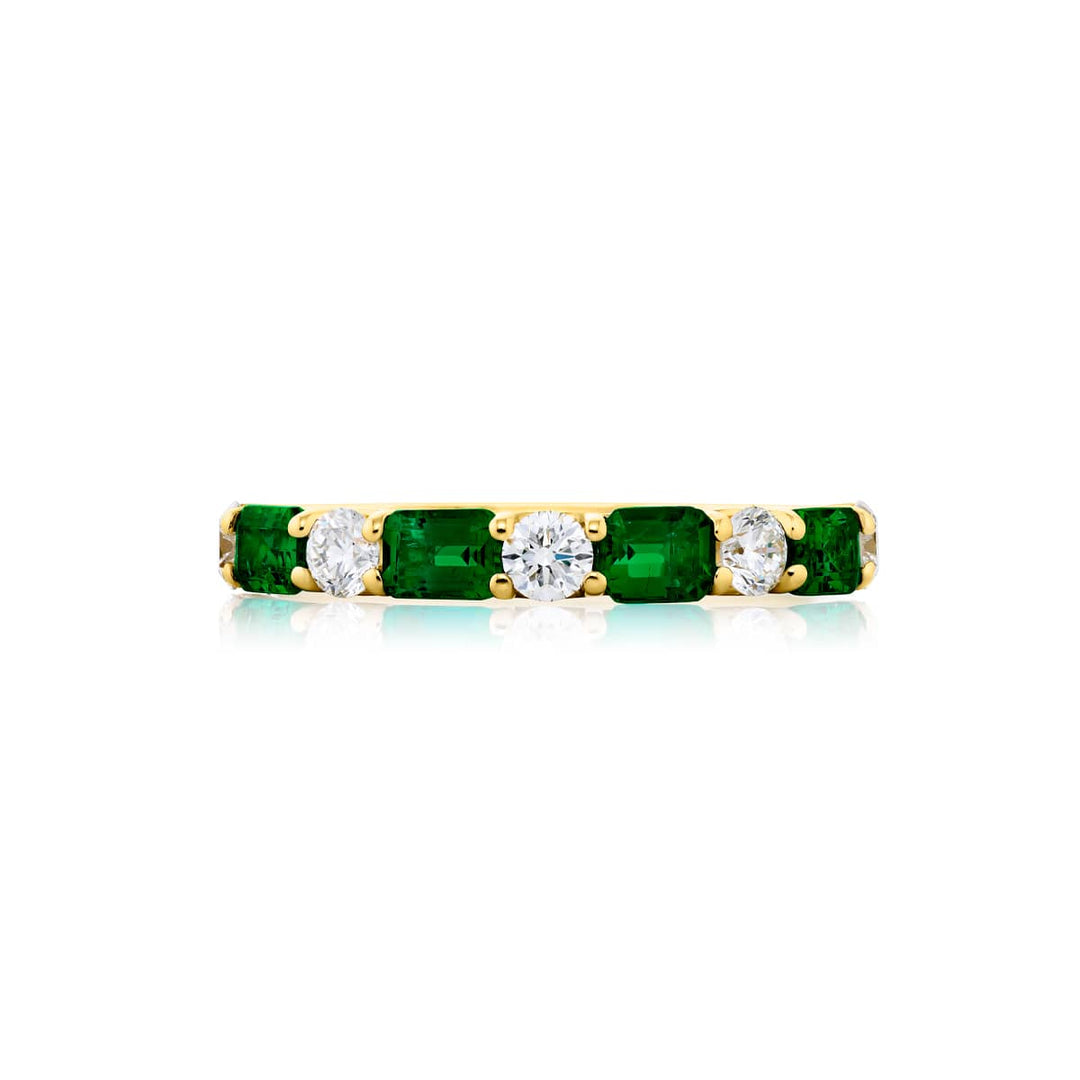 Elegance Elevated: Our signature East-West Emerald and Diamond Band. These gorgeous emerald-cut emeralds embraced with round diamonds are handcrafted in 18K yellow gold.