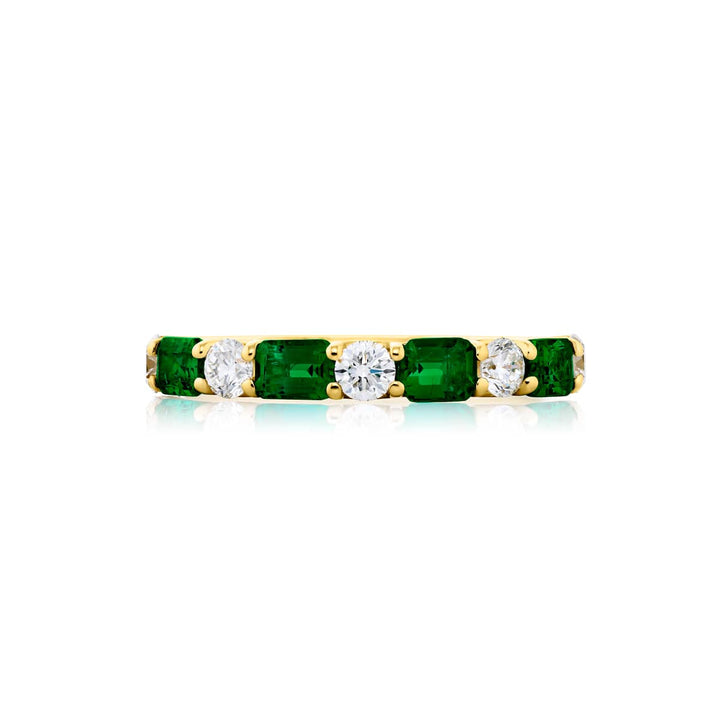 Elegance Elevated: Our signature East-West Emerald and Diamond Band. These gorgeous emerald-cut emeralds embraced with round diamonds are handcrafted in 18K yellow gold.