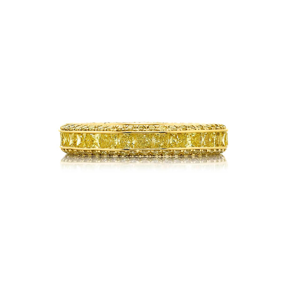 Alluring Eternity: Our beautiful single row Fancy Yellow Diamond Eternity Band. These stunning princess-cut fancy yellow diamonds blend with pave diamonds and are handcrafted in 18KY gold.
