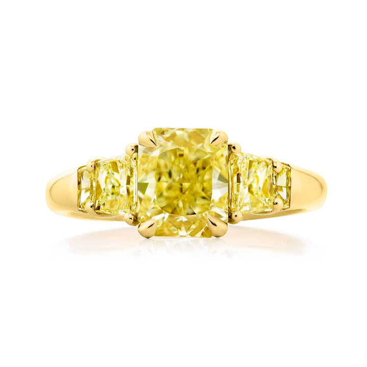 Dazzling Brilliance: Our timeless 1.64 ct. GIA certified Fancy Yellow Diamond Ring. This gorgeous radiant-cut fancy yellow diamond flanked by trapezoid fancy yellow diamonds is handcrafted in 18K yellow gold.
