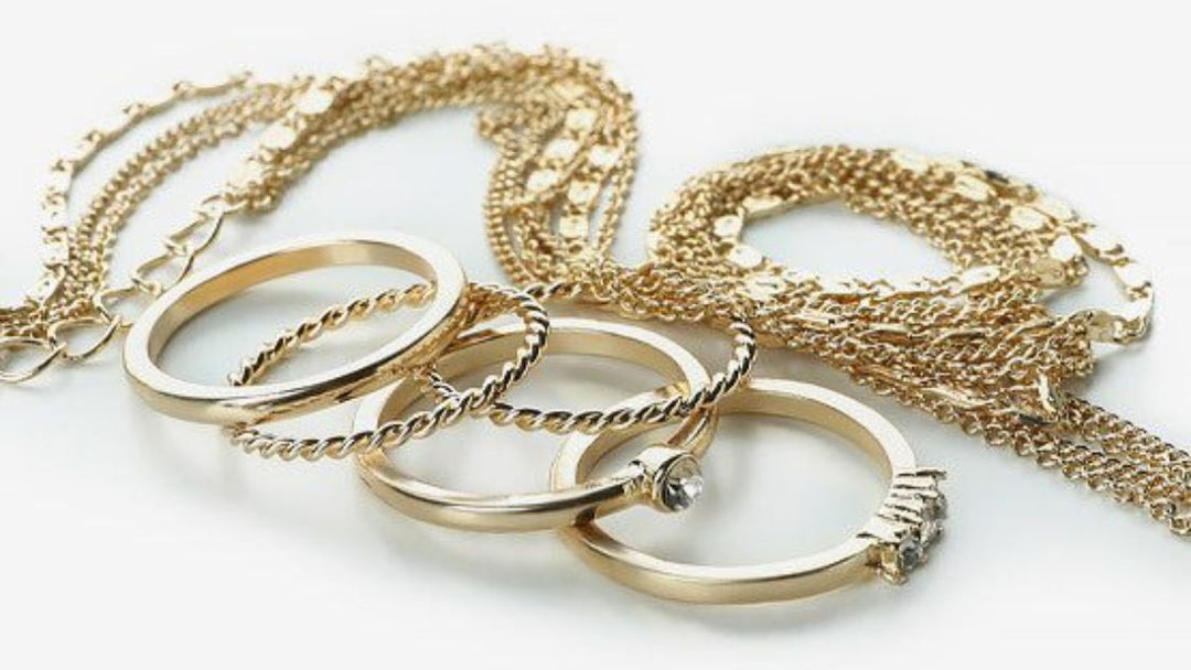 Gold jewelry including rings and necklaces on a white background